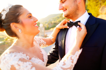 Beautiful wedding couple kissing in the sun near road and trees