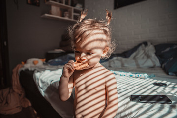 child with tails on his head favors morning in bed in his parents' room on a sunny day. concept of a family of typical, ordinary home-like recreation of a real middle-income family in Europe