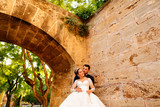Happy wedding couple posing in park under old arch