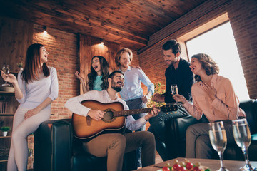 Close up photo pleasant serenate long waited gathering best friends buddies hang out vocal soloist play guitar she her ladies he him his guys wear dress shirts formal wear sit sofa loft room indoors