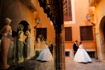 Beautiful wedding couple posing on streets near showcase with mannequins