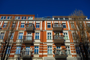 Fototapeta na wymiar high contrasted picture of apartment house in berlin with brick facade and white ornaments