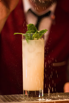 Refreshing cocktail covered in snow with bartender in tie