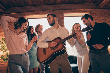 Company of nice-looking lovely charming elegant classy cheerful cheery ecstatic positive careless guys ladies having fun birthday event disco guitar player in industrial loft interior room indoors