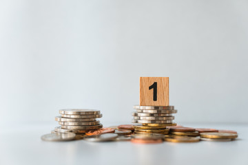 Closeup wooden block number one on stack coins using as business and finance concept