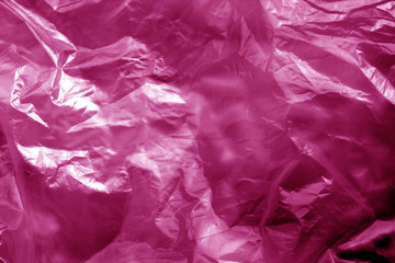 Crumpled transparent plastic  surface in pink tone.