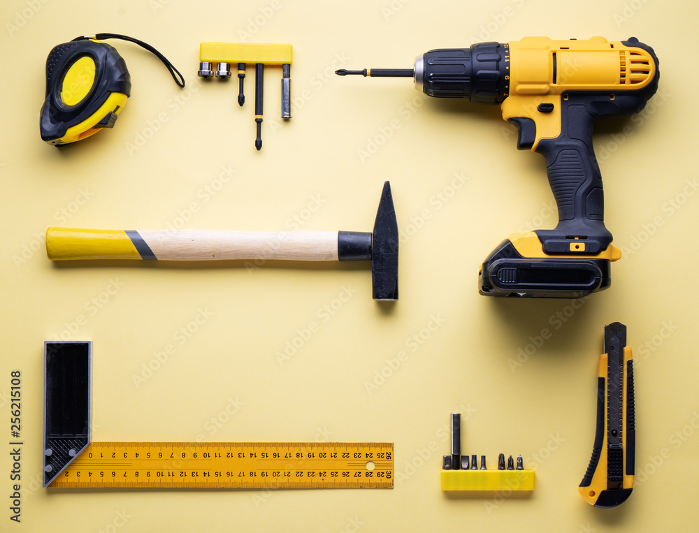 Wall mural flat layout of yellow hand tools on a yellow background.