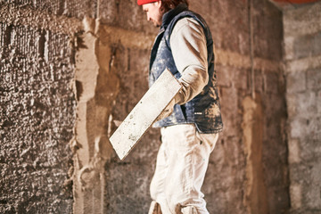 Real construction worker making a wall inside the new house.