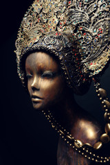 Head of mannequin in decorated bronze kokoshnick, dark studio background