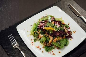 Salad with shrimps and greens on a plate on the table