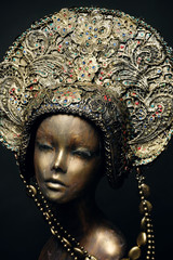 Head of mannequin in decorated bronze kokoshnick, dark studio background