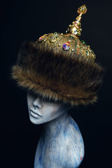 White head of mannequin in fur rich historical head-wear, dark studio background