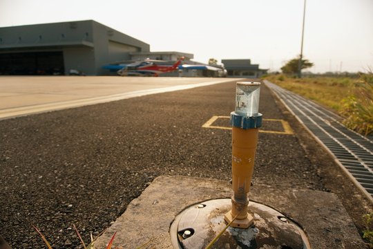 Taxiway light with helicopter on background. Helicopter parking on ramp with taxiway light on foreground.