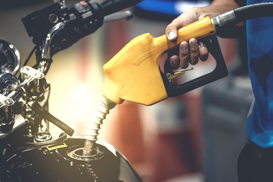 Hand refilling the motorbike with fuel at the refuel station.