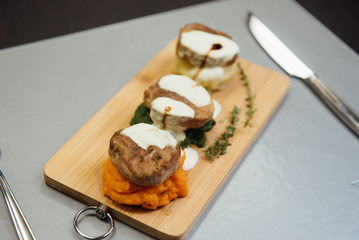 Melted cheese on meat patties on a cutting board on the table
