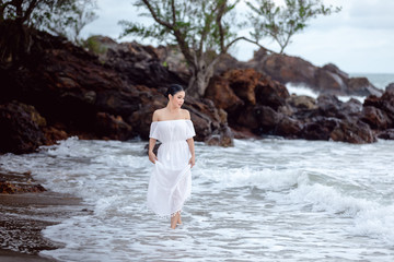 thai girl  tourists in white dress happily walking at the beach on weekend
