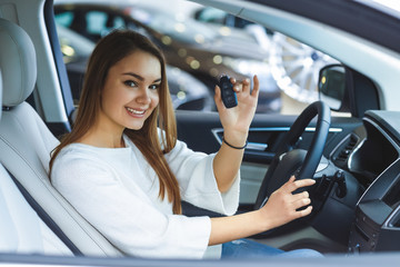Beautiful happy woman choosing a car at the dealership