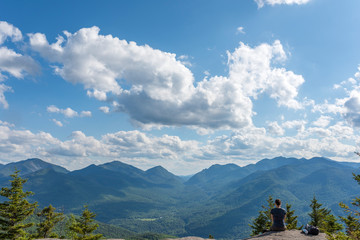 a woman peers at the endless view while perched on a rock