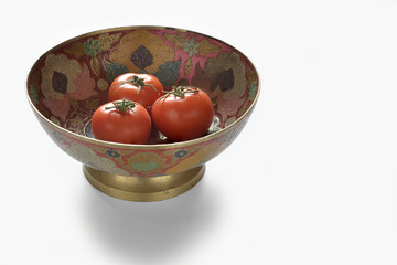Red tomatoes in a metal bowl.