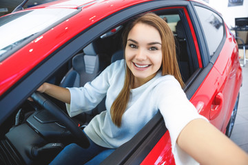 Beautiful happy woman choosing a car at the dealership