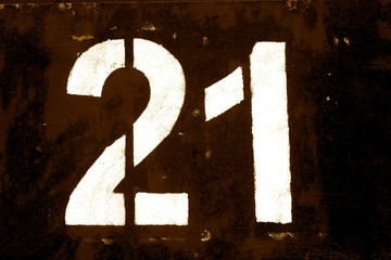 Number 21 in stencil on metal wall in brown tone.