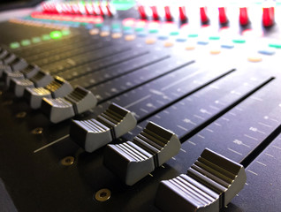 Professional digital audio mixing console with faders and adjusting knobs.