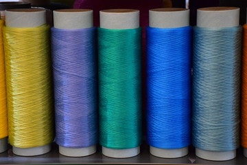 Five bobbins with polypropylene thread, front view. Large colorful technical thread set in rainbow mood. Multicolor bobbin thread. Polypropylene multifilament yarns. The concept of sewing production.