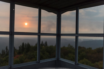 abandoned fire tower during sunset with low lying wispy clouds