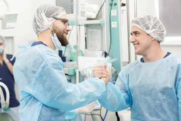 Happy surgeons handshaking after successful operation at the hospital