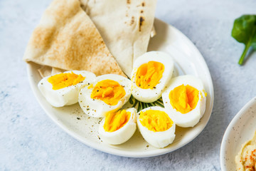 Boiled eggs cutted in halfs seasoned with pepper and salt with pita bread on a plate, appetizers meal