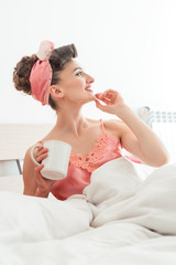 Woman waking up in her bed drinking a cup of coffee