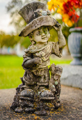 Fototapeta premium A aged alabaster boy grave statue on a grave. The boy is holding his hat, and there is also a dog t as well by his leg. The alabaster has discolored from the elements. 