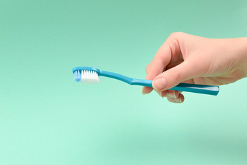 The woman holds toothbrushes in her hand on a green background.
