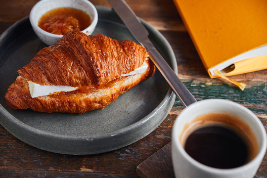 Croissant with brie cheese and jam served with coffee