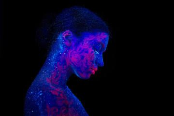 Profile portrait of a beautiful girl alien. Ultraviolet body art blue night sky with stars and pink jellyfish, head tilted down.