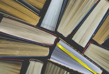 Naklejka premium Lots of colourful thick open books stand on a dark background