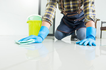 man with cloth cleaning floor in home uses rag and fluid in a spray