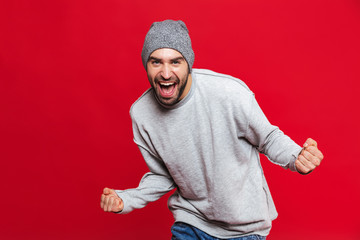 Fototapeta premium Image of happy man screaming and rejoicing isolated over red background