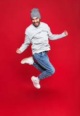 Full length photo of optimistic man smiling and jumping isolated over red background