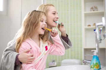Happy family mother and child girl cleans teeth with toothbrush