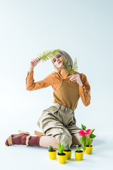 Fototapeta na wymiar beautiful stylish girl posing with fern leaves near flower pots on white