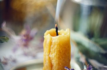 The wax candle, made by hand, is extinguished and emits smoke from the heated wick