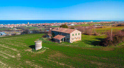 Countryside farm house with sea and a city on the background, aerial view from a drone