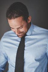 Young businessman smiling while standing against a gray backgrou