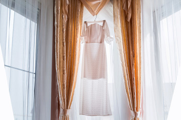 Wedding dress hanging in the living room on the window