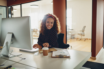 Smiling businesswoman sitting at her workstation in a large offi