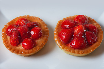 Basket-cakes with mascarpone cheese and decorated with strawberry on white plate. High Key. Close up. Selective focus. Top view.