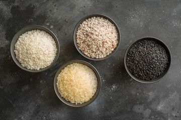 Different varieties of rice. Black rice in bowl on black. Top view.
