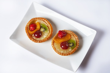 Basket-cake decorated with different fruit on white table. High key. Top view. Selective focus.