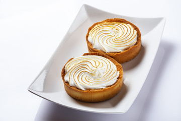 Basket-cake with meringue on white plate. High key. Top view. Selective focus.